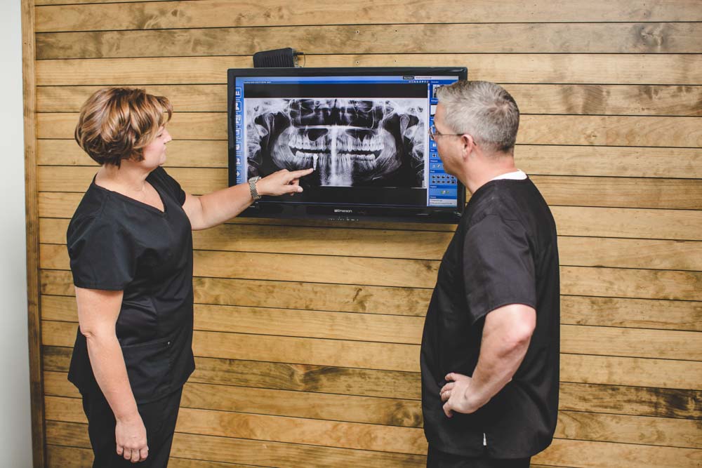 Dentists discuss patient x-rays on a monitor