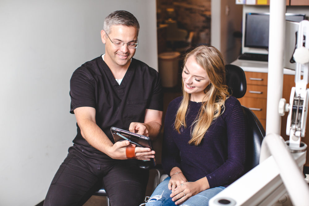 Dr. Hammontree shows a patient an iPad screen while explaining a dental procedure