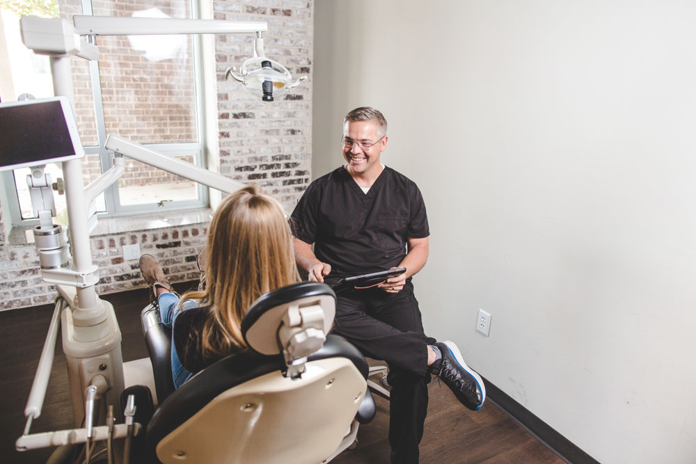 Dr. Hammontree speaks to a dental patient who is seated in an exam chair