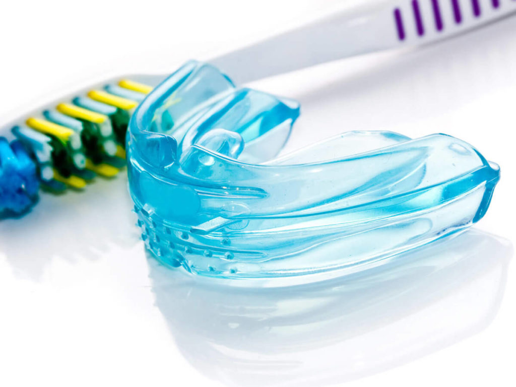 blue mouth guard laying next to a tooth brush