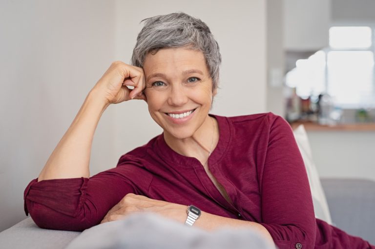 An older woman sitting on a couch and smiling